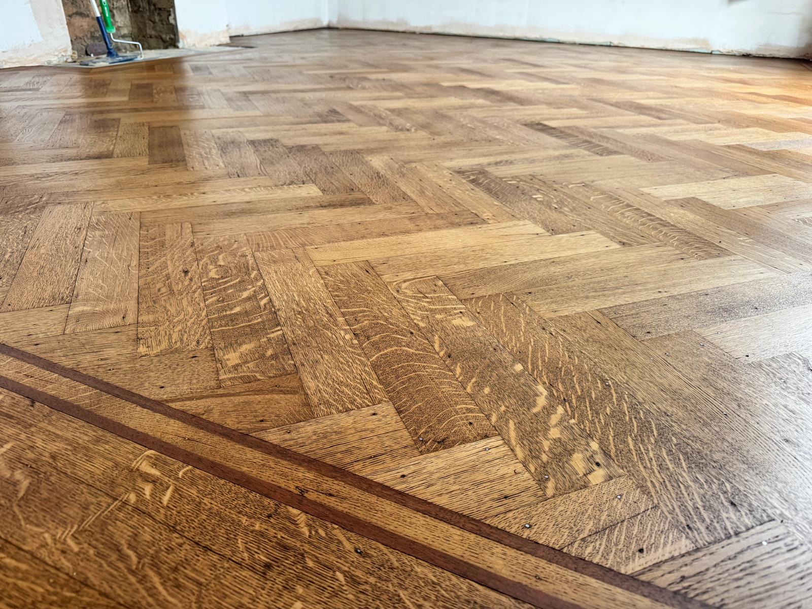 Herringbone parquet with a dark border inlay, before and after sanding and refinishing, after